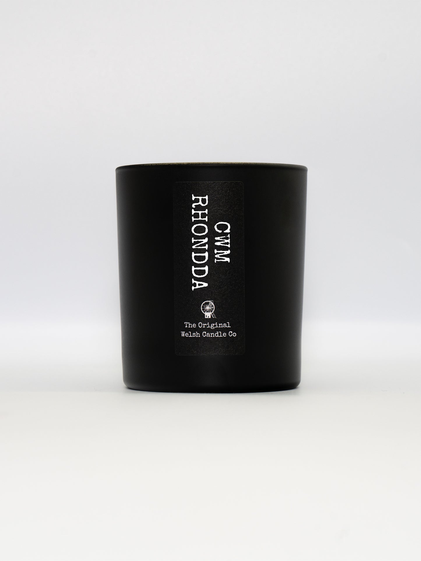 a matt black glass jar with a label saying CWM RHONDDA, filled with a luxury soy scented candle