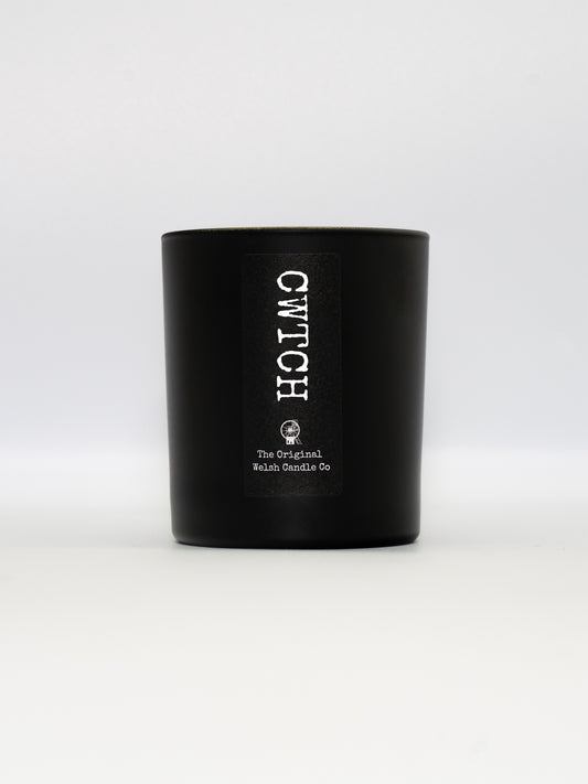 A luxury matt black glass jar, containing a soy scnted candle fragranced with rose and oud